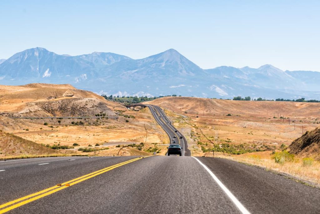 Lege tweebaansweg loopt door een droge vallei recht op een bergketen af in Colorado