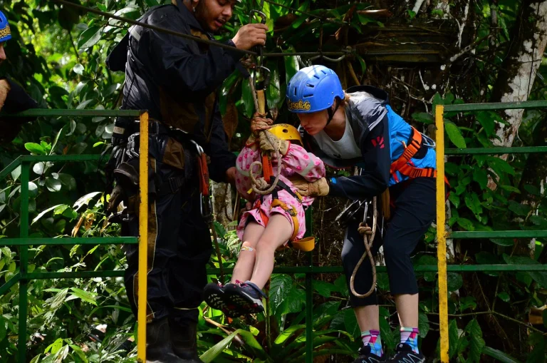Gids en begeleidster maken een klein meisje met helm vast aan de kabel voor de ecoglide zipline in het Costa Ricaanse regenwoud