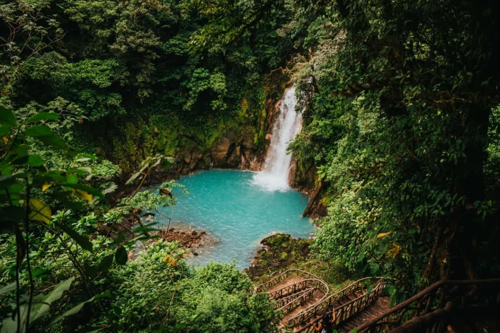 Smalle waterval stort neer in een helder turkooizen poel omringd door dichte tropische jungle in Costa Rica