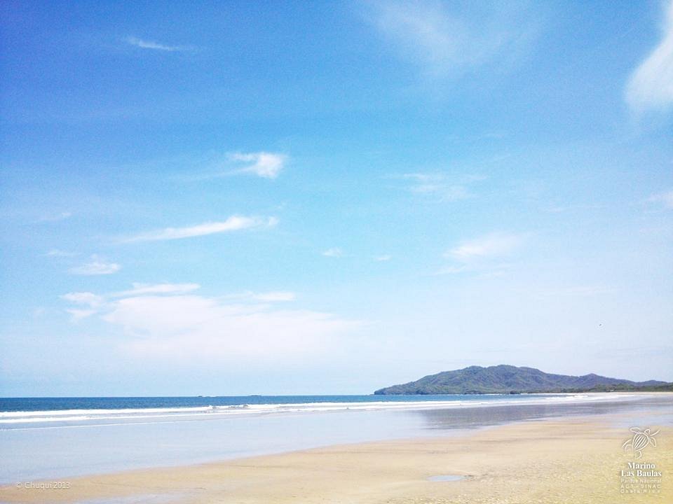 Rustig zandstrand met kalm water en een heuvel in de verte bij het Las Baulas National Marine Park in Costa Rica