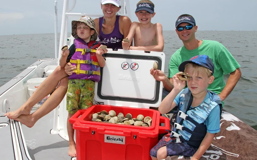 Een familie met kinderen in zwemvesten poseert met verse schelpen op een boot bij Crystal River in Florida