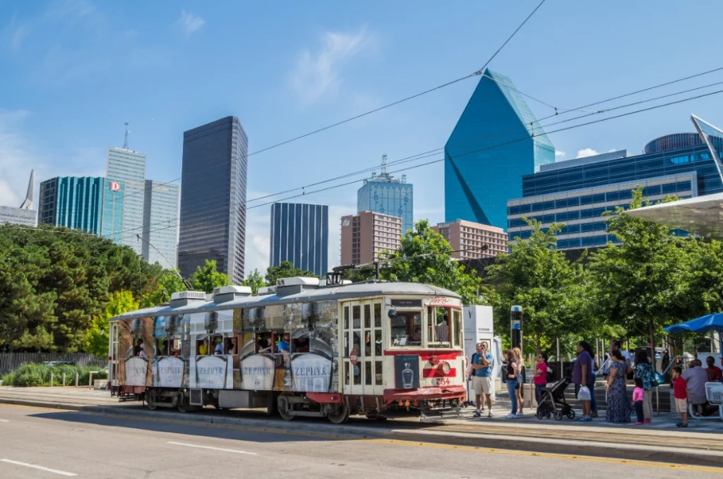 Historische rode tram McKinney Avenue Trolley met passagiers, met de wolkenkrabbers van Dallas op de achtergrond