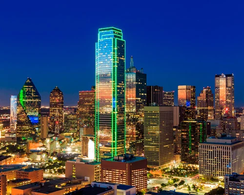 Verlichte wolkenkrabbers van Dallas bij nacht, met de groen omlijnde Bank of America Plaza als hoogste toren