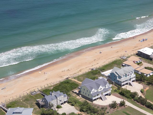 Luchtfoto van houten strandhuizen op palen langs een zandstrand met golvende zee in de Deep South