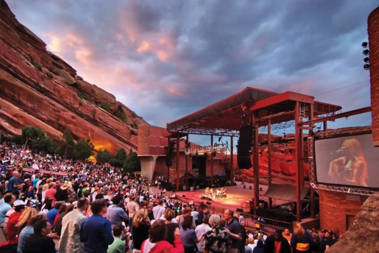Bezoekers kijken bij zonsondergang naar een concert in het rotstheater Red Rocks Amphitheatre nabij Denver, met roodgekleurde rotswanden op de achtergrond