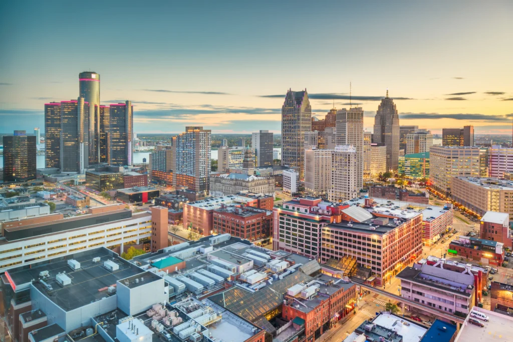 Skyline van Detroit met verlichte wolkenkrabbers tegen een oranje avondlucht in Michigan