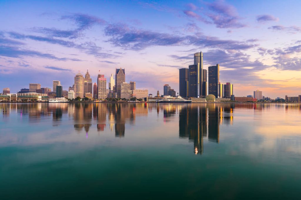 Wolkenkrabbers van Detroit inclusief de ronde torens van het Renaissance Center weerspiegeld in het rustige water van de rivier bij zonsondergang
