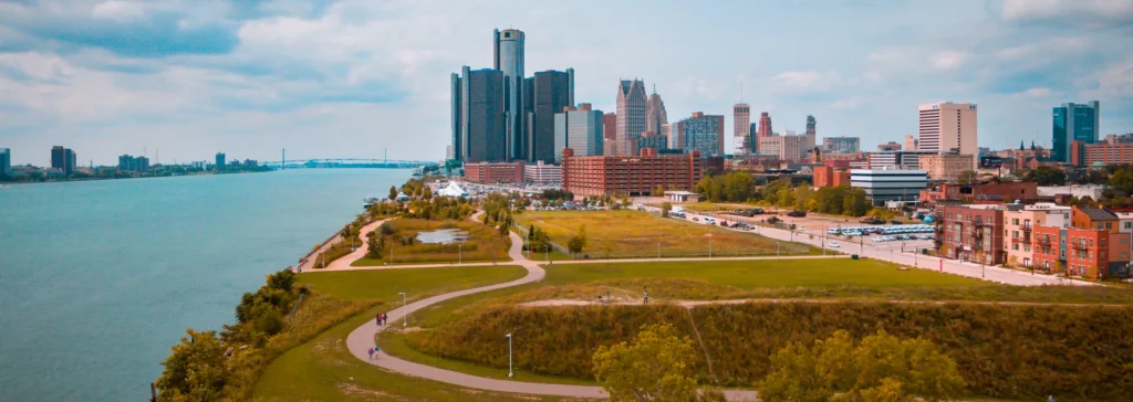 Groen wandelpark met een vijver langs de oever van de Detroit River met de wolkenkrabbers van Detroit op de achtergrond