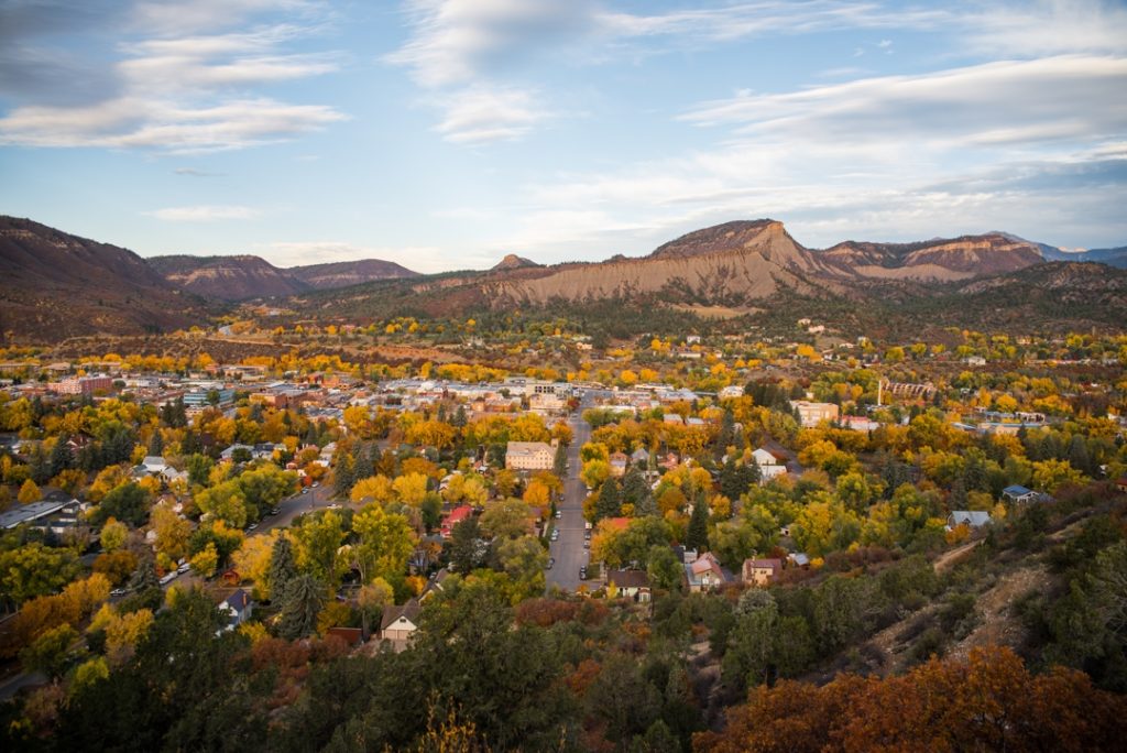 Luchtfoto van de stad Durango met huizen tussen herfstbomen en kale rode rotsformaties op de achtergrond in Colorado