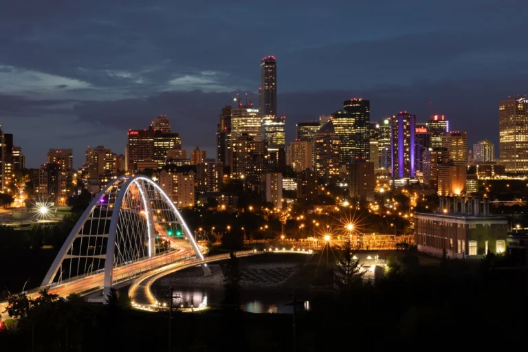 Nachtelijke skyline van Edmonton met een verlichte boogbrug over de rivier en fonkelende wolkenkrabbers op de achtergrond