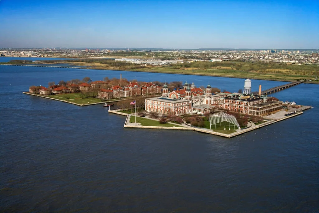 Luchtfoto van de historische gebouwen van Ellis Island omringd door water met de skyline van New York op de achtergrond