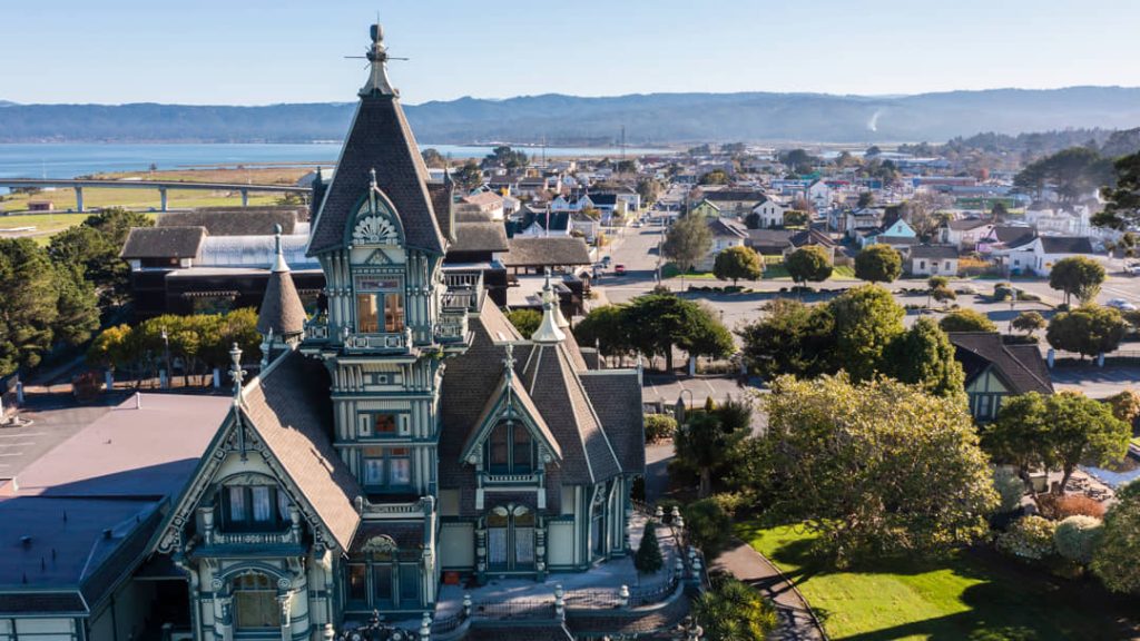 Uitbundig versierd Victoriaans huis met torentjes en puntdaken in Eureka, met de stad en de baai op de achtergrond