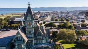 Uitbundig versierd Victoriaans huis met torentjes en puntdaken in Eureka, met de stad en de baai op de achtergrond