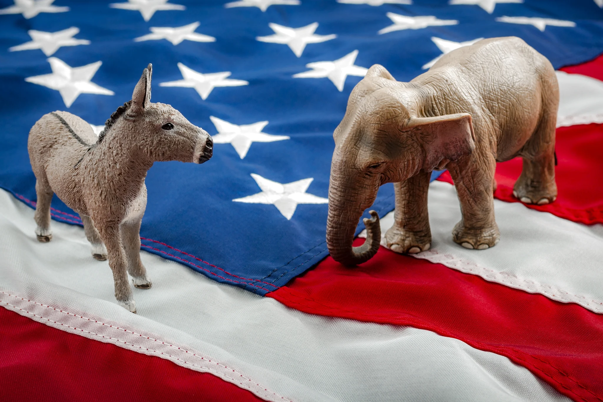 Miniatuurbeeldjes van een ezel en een olifant, de symbolen van de Democraten en Republikeinen, op een Amerikaanse vlag