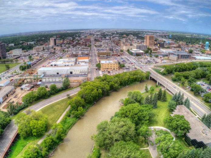 Luchtfoto toont de gebouwen van het centrum van Fargo naast een bochtige rivier omzoomd door bomen