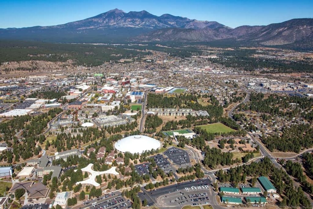 Luchtfoto van de stad Flagstaff omringd door bos met de besneeuwde toppen van de San Francisco Peaks op de achtergrond