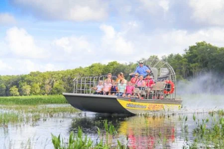 Groep toeristen vaart met een airboat door het moerasgebied van Florida, met opspattend water en groen op de achtergrond