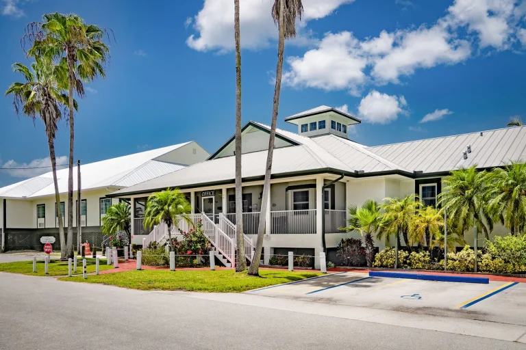 Zonnig wit kantoorgebouw met veranda en trapjes, omgeven door palmbomen bij Everglades National Park in Florida