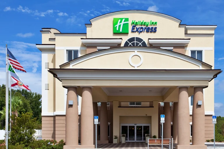 Beige gebouw van Holiday Inn Express in Crystal River met een overdekte entree op zuilen en Amerikaanse en Florida-vlaggen ervoor