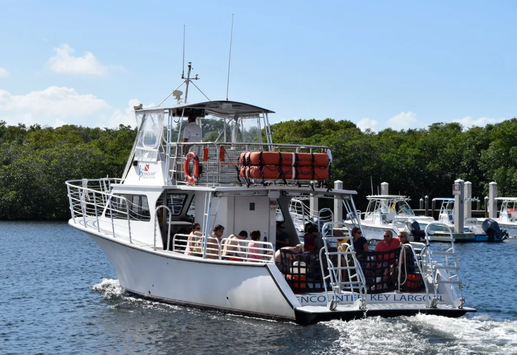 Een witte duikboot met passagiers vaart weg van de haven in Key Largo, Florida Keys, met mangroves op de achtergrond