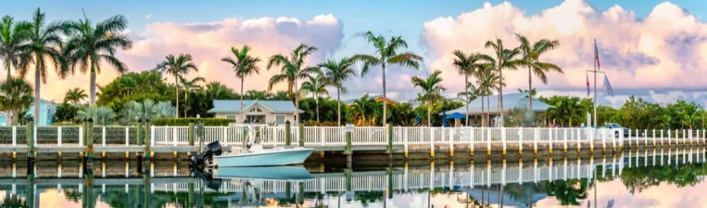 Blauwe vissersboot afgemeerd bij een witte houten steiger met palmbomen en huisjes op de achtergrond in de Florida Keys
