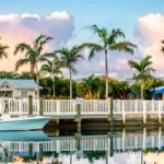 Blauwe vissersboot afgemeerd bij een witte houten steiger met palmbomen en huisjes op de achtergrond in de Florida Keys