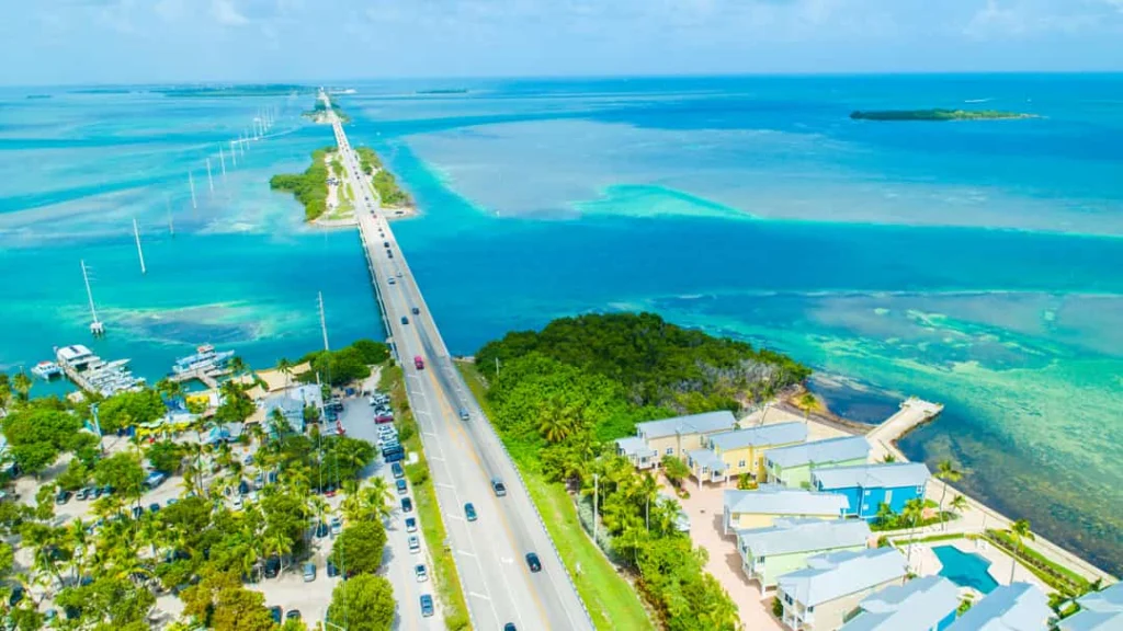 Luchtfoto van een lange brug over turquoise water met kleurrijke huizen en boten op een eilandje in de Florida Keys