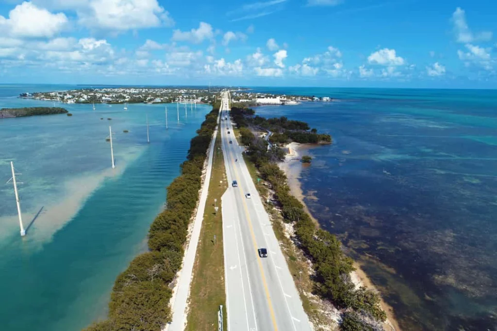 Luchtfoto van een lange rechte brug die door turquoise water tussen eilandjes met palmbomen loopt in de Florida Keys