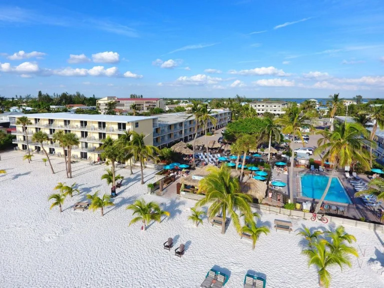 Luchtfoto van een hotelresort met zwembad, palmbomen en ligstoelen op het witte strand bij Fort Myers in Florida