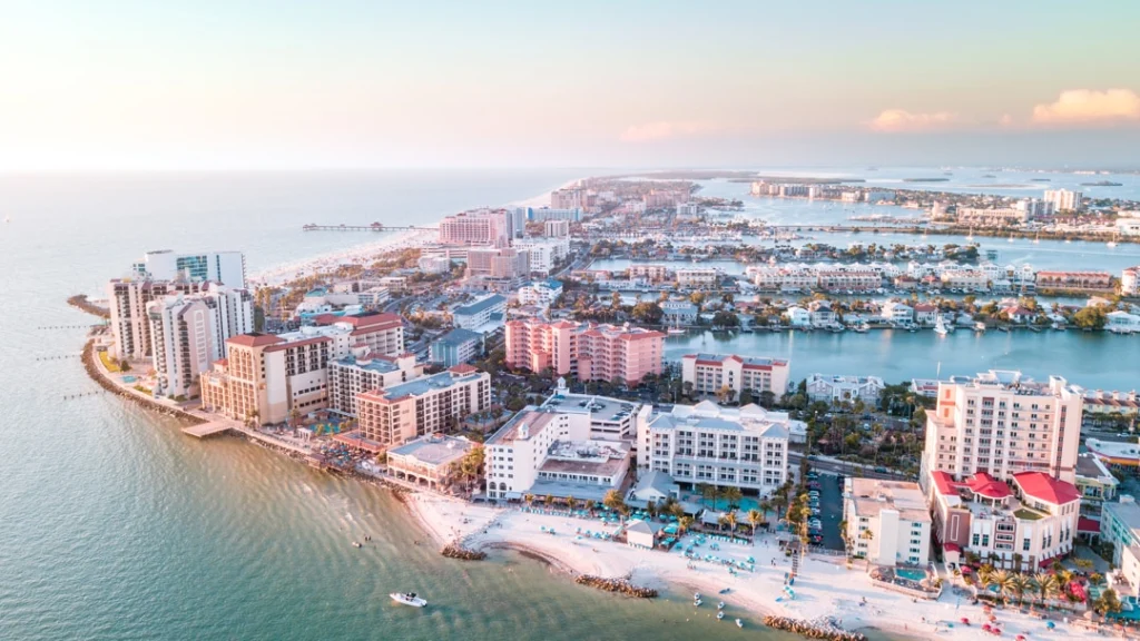 Luchtfoto van een Florida kustplaats met hoge hotels, wit strand en jachthaven bij zonsondergang