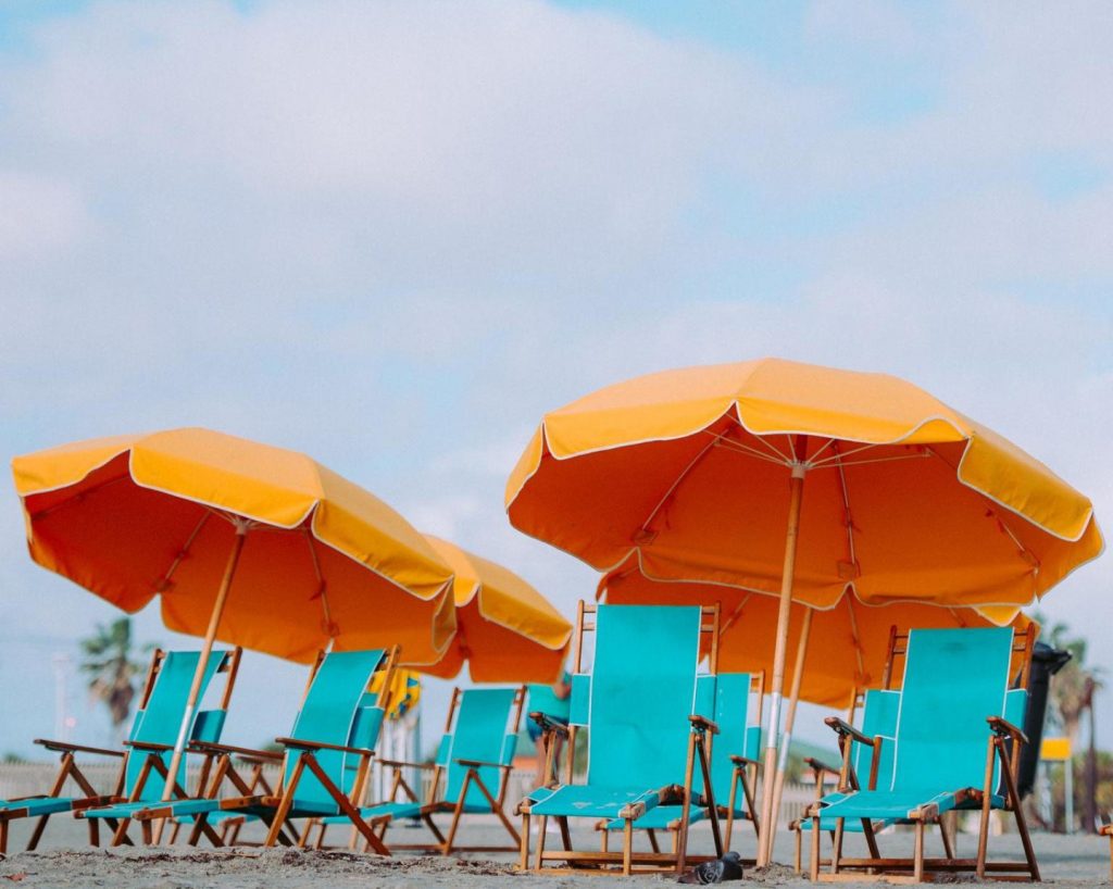 Rijen oranje strandparasols met turquoise strandstoelen eronder opgesteld op een zandstrand in Florida