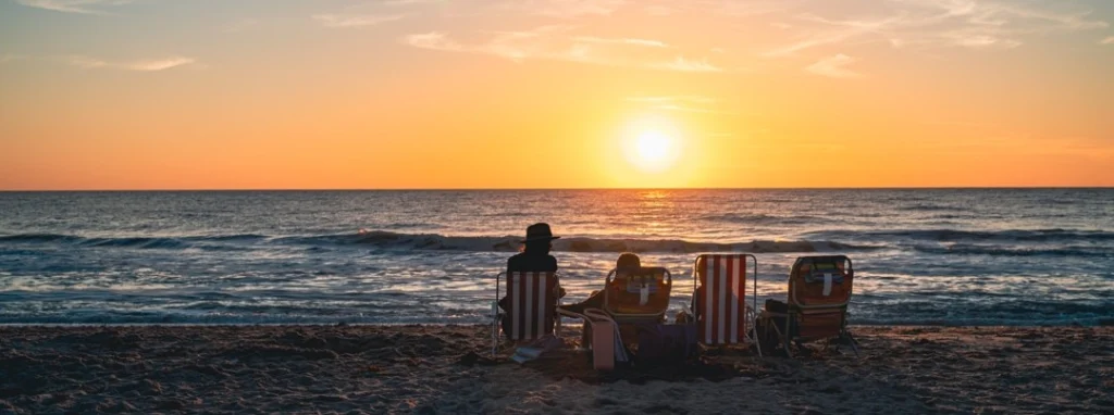 Silhouetten van een gezin in strandstoelen kijken naar de zonsondergang boven zee op een strand in Florida