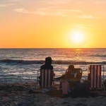 Silhouetten van een gezin in strandstoelen kijken naar de zonsondergang boven zee op een strand in Florida