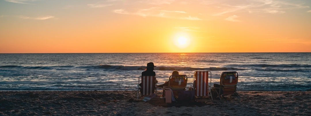 Silhouetten van een gezin in strandstoelen kijken naar de zonsondergang boven zee op een strand in Florida