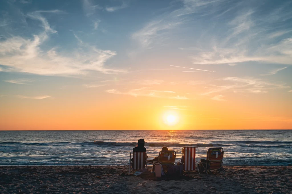 Groepje strandstoelen op het zand terwijl de zon ondergaat boven de zee op een strand in Florida