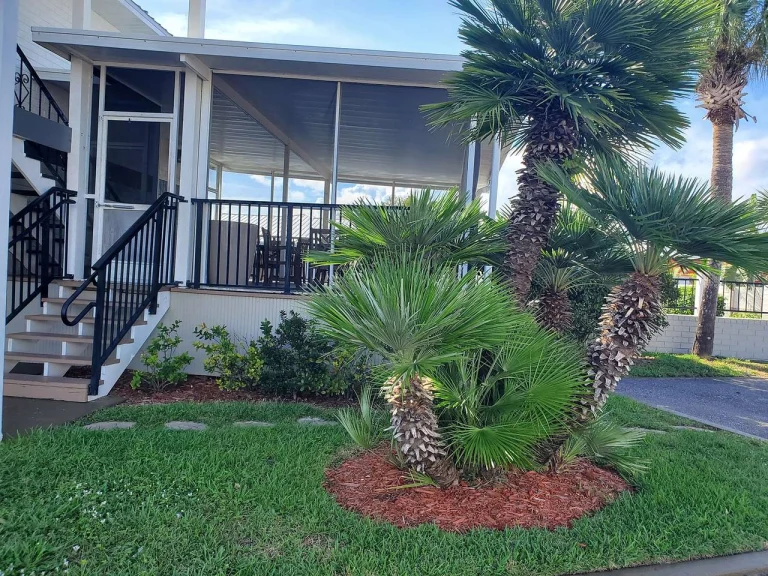 Een huis in Florida met een overdekte, afgeschermde veranda en een voortuin met groene gazon en palmbomen