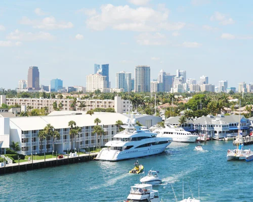 Luxe jachten liggen aan de kade met op de achtergrond de wolkenkrabbers van de skyline van Fort Lauderdale