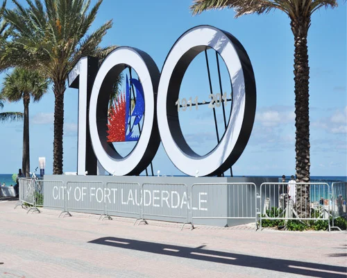 Groot cijferbeeld met het getal honderd en de tekst City of Fort Lauderdale tussen palmbomen aan het strand