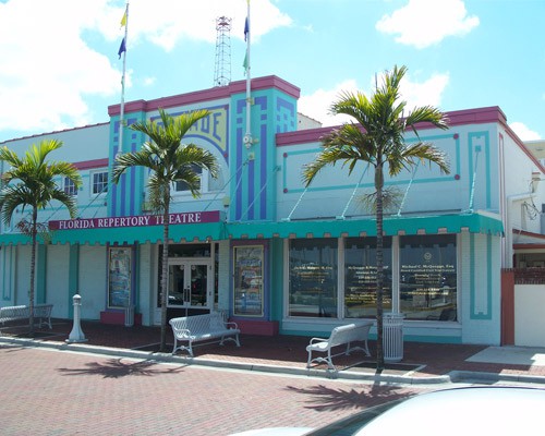Kleurrijk turquoise en roze theatergebouw met palmbomen en bankjes voor de deur in het centrum van Fort Myers