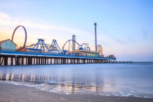 Pretpark op een lange pier met een achtbaan en reuzenrad dat over het water van de Golf van Mexico uitsteekt bij Galveston