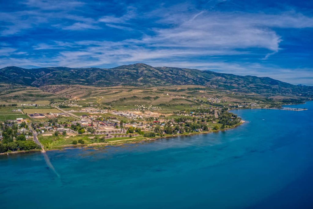 Luchtfoto van het plaatsje Garden City aan de turquoise oever van Bear Lake, omringd door glooiende heuvels