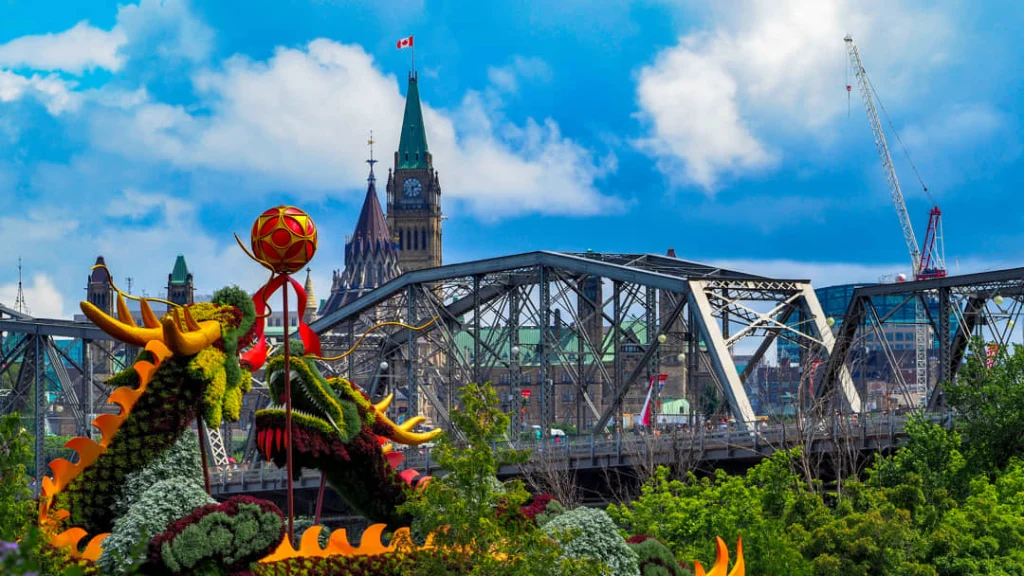 Kleurrijke sculptuur van een draak gemaakt van bloemen en planten met het Canadese parlementsgebouw op de achtergrond bij Gatineau