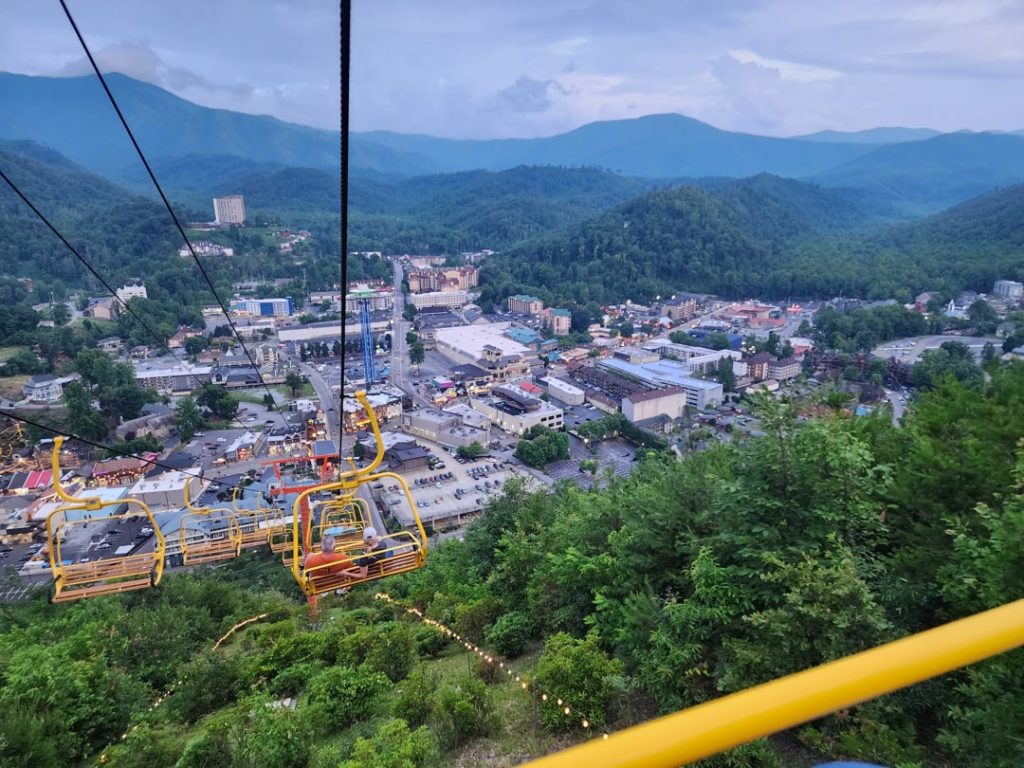 Blik vanaf een gele stoeltjeslift over het centrum van Gatlinburg met de Great Smoky Mountains op de achtergrond