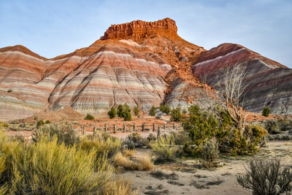Een rood-wit gestreepte rotsformatie (hoodoo) omringd door struikgewas in de woestijn van Utah
