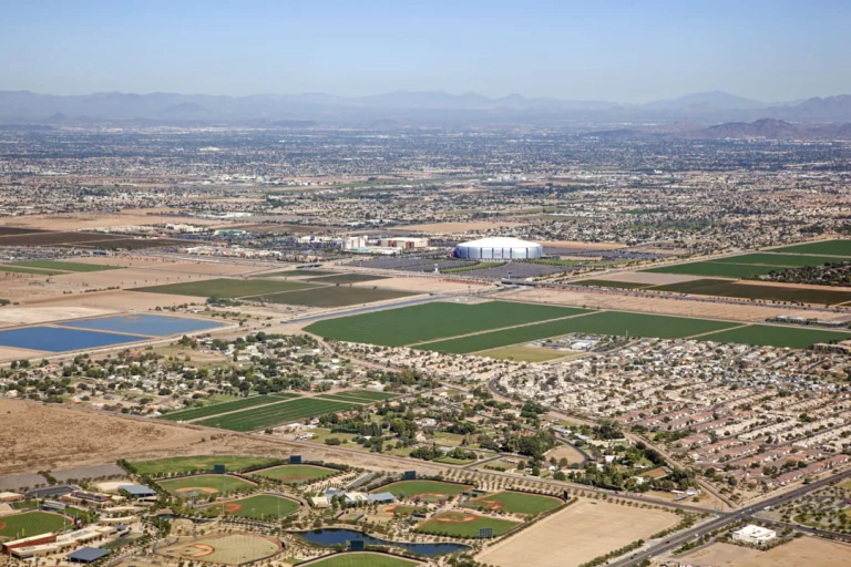 Luchtfoto van Glendale bij Phoenix met een opvallend wit ovaal stadion omringd door akkers, woonwijken en sportvelden