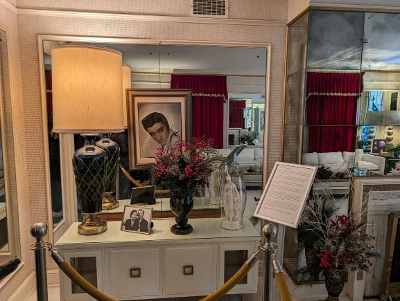 Interieur van een kamer in Graceland Memphis met een geschilderd portret, tafellamp, bloemenvaas en oude fotolijst op een wit dressoir