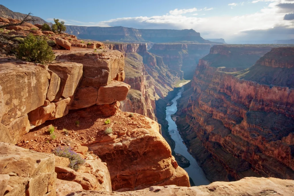 Steile rode rotswanden dalen honderden meters af naar de kronkelende Coloradorivier gezien vanaf Toroweap Point in de Grand Canyon