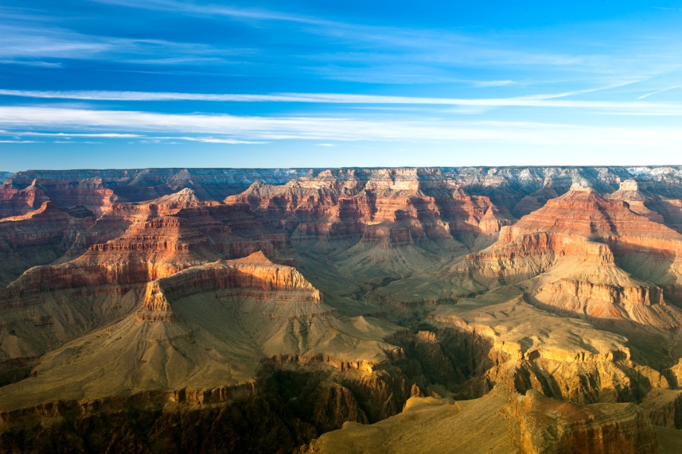 Panoramisch uitzicht over de gelaagde rotsformaties van de Grand Canyon onder een blauwe lucht