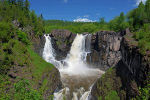 Twee waterstromen storten naast elkaar in een rotsachtige kloof bij High Falls in Grand Portage, omgeven door bos