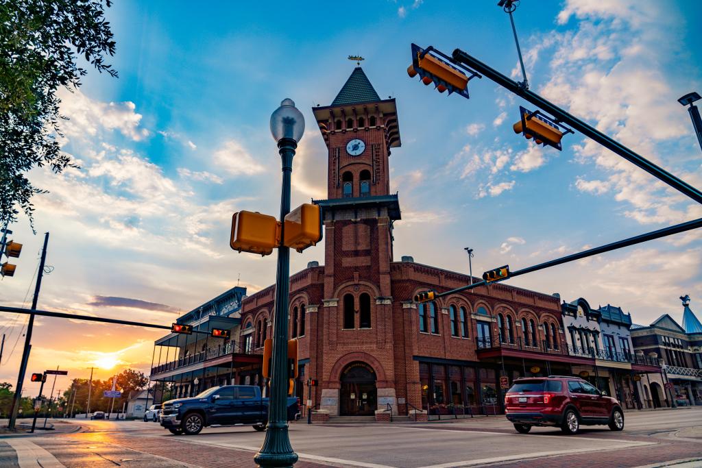 Bakstenen klokkentoren met puntdak op een kruispunt in het historische centrum van Grapevine, Texas, bij zonsondergang